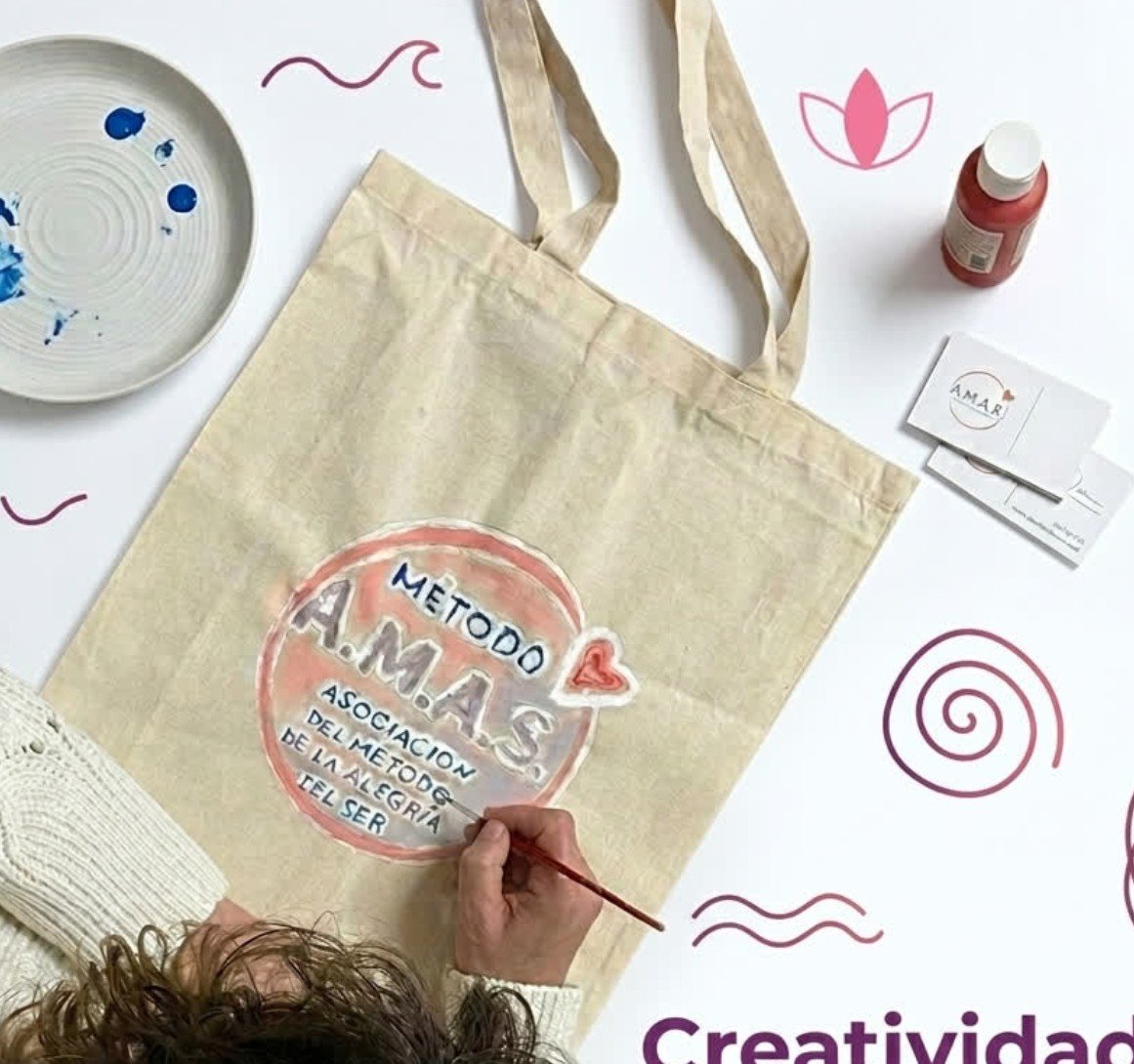 Persona pintando a mano una bolsa de tela con el método A.M.A.S