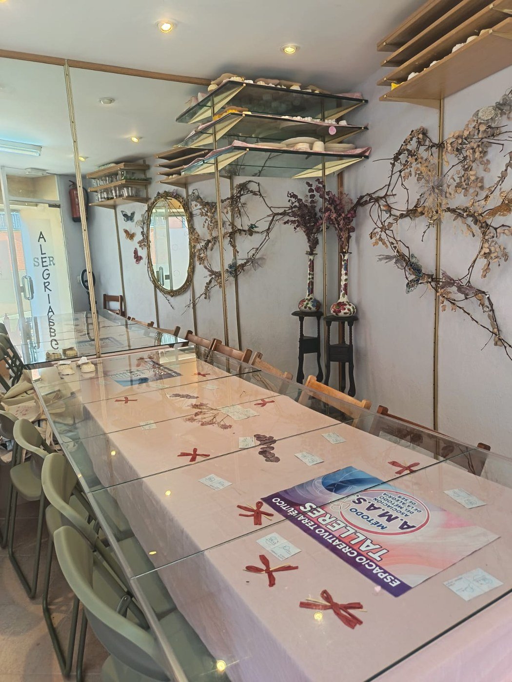 La sala donde Leticia imparte sus talleres: mesa larga, espejos y flores secas en un ambiente cálido